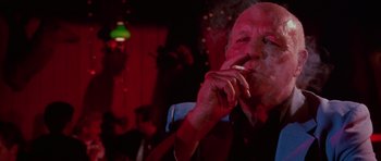 Movie still from “Reservoir Dogs” (1992), directed by Quentin Tarantino – An older man smoking a cigarette in a dark room; Close Up shot, Low angle