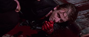 Movie still from “Reservoir Dogs” (1992), directed by Quentin Tarantino – A man in a black jacket and red gloves; Close Up shot, High angle