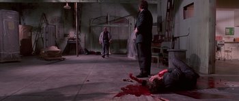 Movie still from “Reservoir Dogs” (1992), directed by Quentin Tarantino – Two men in suits stand over a dead body; Wide shot, High angle