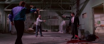 Movie still from “Reservoir Dogs” (1992), directed by Quentin Tarantino – Two men in a room holding guns and aiming at each other; Wide shot, Low angle