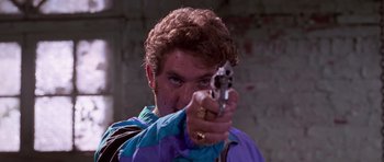 Movie still from “Reservoir Dogs” (1992), directed by Quentin Tarantino – A man holding a gun pointed at the camera; Close Up shot, Low angle