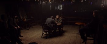 Movie still from “Ride Along” (2014), directed by Tim Story – Two men are sitting at a table in a dark room; Wide shot, Over the shoulder angle