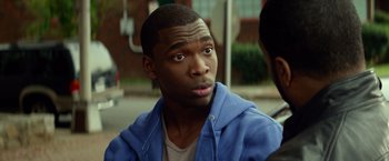 Movie still from “Ride Along” (2014), directed by Tim Story – A young man is looking at the camera while sitting on a bench; Close Up shot, Over the shoulder angle