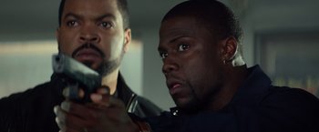 Movie still from “Ride Along” (2014), directed by Tim Story – Two men looking at the camera while holding a cell phone; Close Up shot, Over the shoulder angle