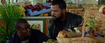 Movie still from “Ride Along” (2014), directed by Tim Story – A man sitting in front of a basket of fruit; Close Up shot, Over the shoulder angle