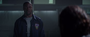 Movie still from “Ride Along” (2014), directed by Tim Story – A man wearing a police uniform standing in front of a door; Medium shot, Over the shoulder angle