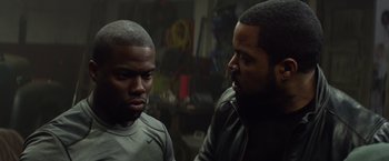 Movie still from “Ride Along” (2014), directed by Tim Story – Two men are talking in a garage; Close Up shot, Over the shoulder angle
