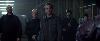 Movie still from “Ride Along” (2014), directed by Tim Story – A group of men standing next to each other in a dark room; Medium shot, Over the shoulder angle