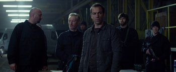 Movie still from “Ride Along” (2014), directed by Tim Story – A group of men standing next to each other in a warehouse; Medium shot, Over the shoulder angle
