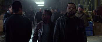 Movie still from “Ride Along” (2014), directed by Tim Story – A group of men standing next to each other in a building; Medium shot, Over the shoulder angle