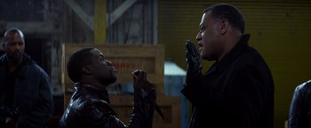 Movie still from “Ride Along” (2014), directed by Tim Story – Two men in leather jackets one is holding a knife and the other is holding a cell phone; Medium shot, Over the shoulder angle