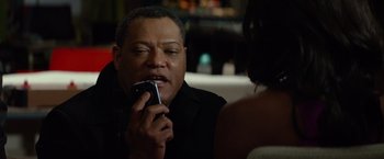 Movie still from “Ride Along” (2014), directed by Tim Story – A man holding a cell phone up to his mouth; Close Up shot, Over the shoulder angle