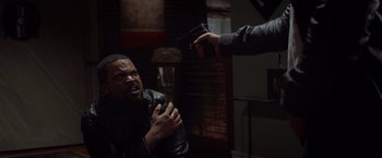 Movie still from “Ride Along” (2014), directed by Tim Story – A man holding a gun up to another man's face; Medium shot, Over the shoulder angle