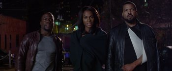 Movie still from “Ride Along” (2014), directed by Tim Story – A woman standing next to two other people; Medium shot, Over the shoulder angle