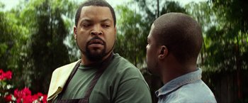 Movie still from “Ride Along” (2014), directed by Tim Story – Two men standing next to each other in front of trees; Close Up shot, Over the shoulder angle