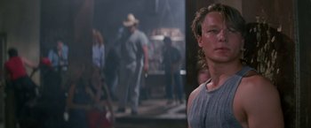 Movie still from “Road House” (1989), directed by Rowdy Herrington – A man standing in front of a group of people; Close Up shot, Over the shoulder angle