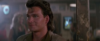 Movie still from “Road House” (1989), directed by Rowdy Herrington – A person with long brown hair; Close Up shot, Over the shoulder angle