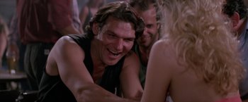 Movie still from “Road House” (1989), directed by Rowdy Herrington – A group of people that are sitting in a room together; Close Up shot, Low angle