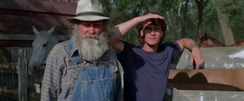 Movie still from “Road House” (1989), directed by Rowdy Herrington – A man with a beard standing next to a man with a hat on; Medium shot, Low angle