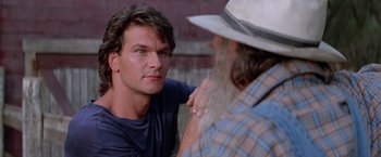 Movie still from “Road House” (1989), directed by Rowdy Herrington – A man is talking to another man in a cowboy hat; Close Up shot, Over the shoulder angle