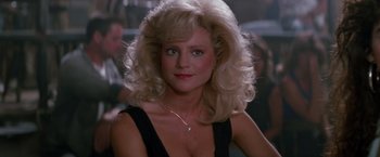 Movie still from “Road House” (1989), directed by Rowdy Herrington – A woman with blonde hair wearing a black top; Close Up shot, Over the shoulder angle