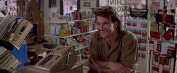 Movie still from “Road House” (1989), directed by Rowdy Herrington – A man sitting in front of a cash register in a store; Close Up shot, Over the shoulder angle