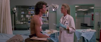 Movie still from “Road House” (1989), directed by Rowdy Herrington – A man and a woman are in a hospital room; Medium shot, Low angle