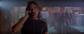 Movie still from “Road House” (1989), directed by Rowdy Herrington – A man talking on a phone while standing next to a pool table; Close Up shot, Low angle
