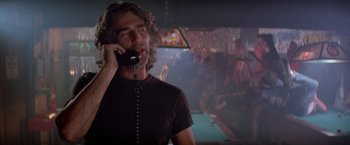 Movie still from “Road House” (1989), directed by Rowdy Herrington – A man talking on a phone while standing in front of a pool table; Close Up shot, Low angle