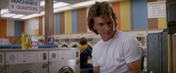 Movie still from “Road House” (1989), directed by Rowdy Herrington – A man in white shirt standing in front of a washing machine; Medium shot, Low angle