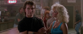 Movie still from “Road House” (1989), directed by Rowdy Herrington – A man and a woman standing next to each other in a room; Medium shot, Low angle