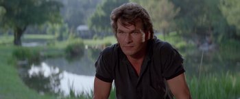 Movie still from “Road House” (1989), directed by Rowdy Herrington – A person sitting in front of a body of water; Close Up shot, Over the shoulder angle