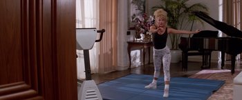Movie still from “Road House” (1989), directed by Rowdy Herrington – A woman is doing exercises in a living room; Wide shot, Low angle