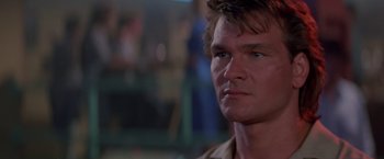 Movie still from “Road House” (1989), directed by Rowdy Herrington – A man's face in a dark room; Close Up shot, Low angle