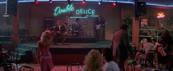 Movie still from “Road House” (1989), directed by Rowdy Herrington – A group of people on a stage playing music; Wide shot, Over the shoulder angle