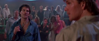Movie still from “Road House” (1989), directed by Rowdy Herrington – A group of people standing in front of a crowd; Medium shot, Over the shoulder angle