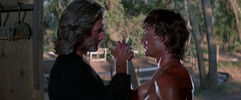 Movie still from “Road House” (1989), directed by Rowdy Herrington – Two men arm wrestling each other in front of trees; Close Up shot, Over the shoulder angle
