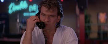Movie still from “Road House” (1989), directed by Rowdy Herrington – A man with long hair talking on a phone; Close Up shot, Low angle