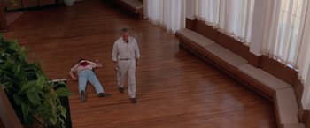 Movie still from “Road House” (1989), directed by Rowdy Herrington – A man standing on a hardwood floor next to another man; Wide shot, High angle