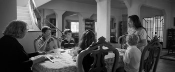 Movie still from “Roma” (2018), directed by Alfonso Cuarón – A group of people sitting around a table; Wide shot, Over the shoulder angle