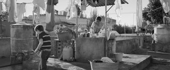 Movie still from “Roma” (2018), directed by Alfonso Cuarón – A woman standing in front of an outdoor market; Wide shot, Low angle