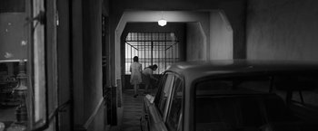 Movie still from “Roma” (2018), directed by Alfonso Cuarón – Two people are walking in a hallway near a car; Extreme Wide shot, High angle