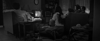 Movie still from “Roma” (2018), directed by Alfonso Cuarón – Two people sitting on a couch watching television; Medium shot, High angle