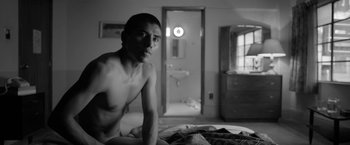 Movie still from “Roma” (2018), directed by Alfonso Cuarón – A man sitting on top of a bed next to a mirror; Medium shot, Low angle