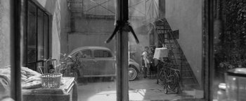 Movie still from “Roma” (2018), directed by Alfonso Cuarón – An old car parked in a garage next to a building; Wide shot, High angle