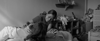 Movie still from “Roma” (2018), directed by Alfonso Cuarón – A young woman is smiling as she looks at her cell phone; Medium shot, High angle