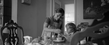 Movie still from “Roma” (2018), directed by Alfonso Cuarón – A woman and a boy are sitting at a table; Medium shot, Low angle