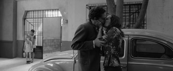 Movie still from “Roma” (2018), directed by Alfonso Cuarón – A man and a woman kissing in front of a parked car; Medium shot, Low angle