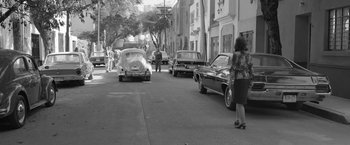 Movie still from “Roma” (2018), directed by Alfonso Cuarón – A woman standing on the side of the street next to a car; Wide shot, High angle