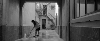 Movie still from “Roma” (2018), directed by Alfonso Cuarón – A woman holding a broom in a courtyard; Wide shot, High angle